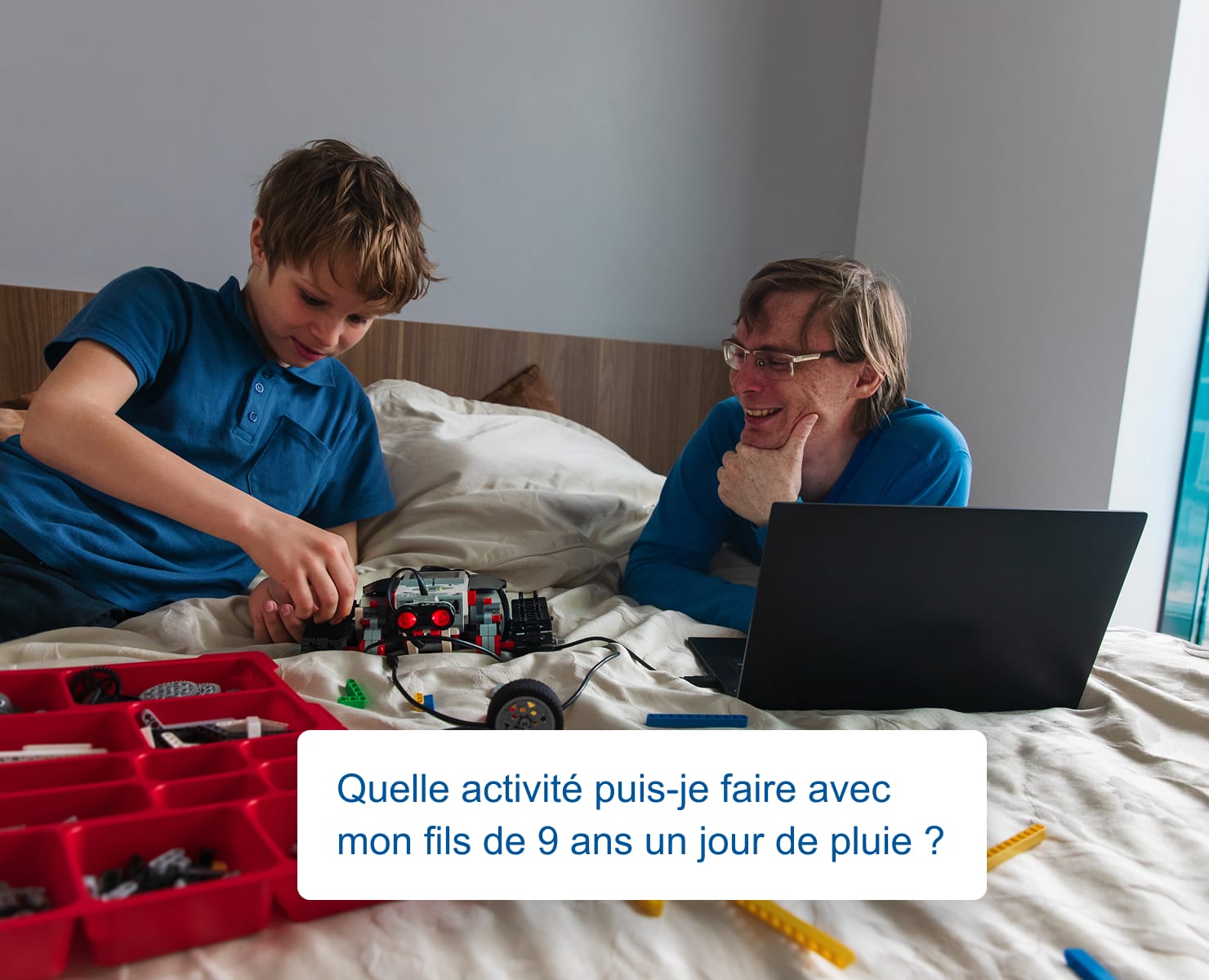 Père et fils sur un lit construisant un robot ensemble, avec un ordinateur portable ouvert affichant une conversation de style Perplexity disant : Quelle activité puis-je faire avec mon fils de 9 ans un jour de pluie ?